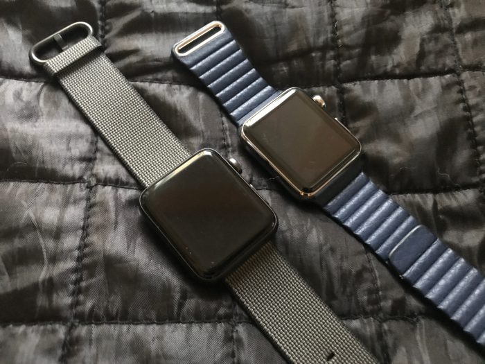 Nailonrannekkeella etualalla uusi Apple Watch Series 2 alumiiniversiona. Vieressä alkuperäinen Watch rungolla ruostumattomasta teräksestä sekä sinisellä nahkarannekkeella.