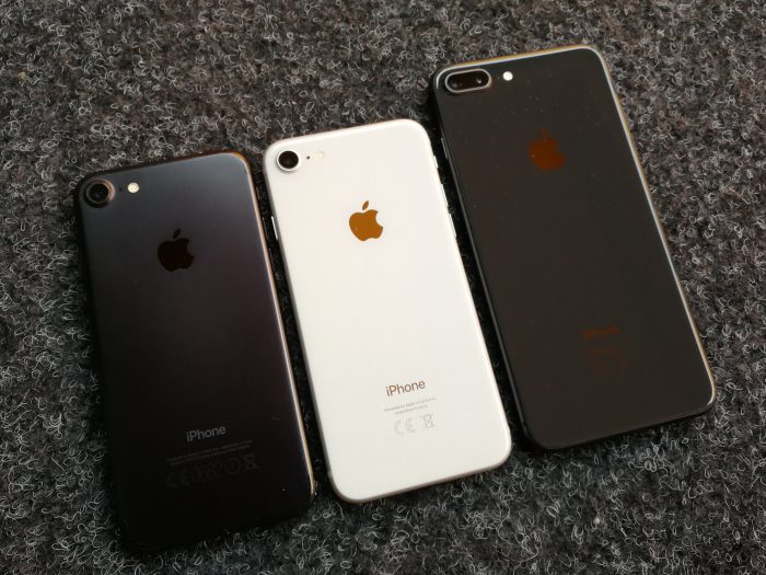 Mattamustan iPhone 7:n rinnalla hopea iPhone 8 valkoisella takapinnalla lasin alla sekä tähtiharmaa iPhone 8 Plus.