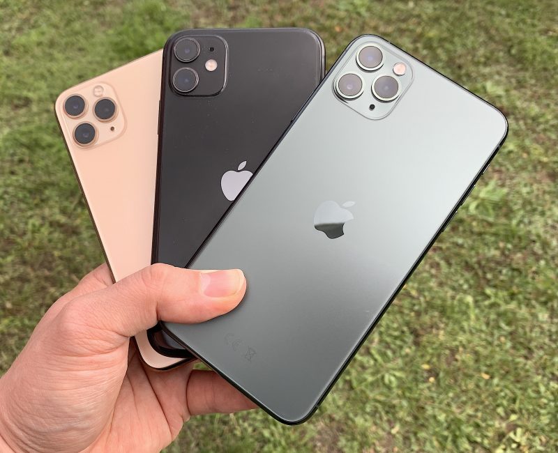 Kuvassa takana kultavärinen iPhone 11 Pro, keskellä musta iPhone 11 ja etualalla keskiyönvihreä iPhone 11 Pro Max. Pro-mallit ovat mattapintaisia, iPhone 11 kiiltävä.