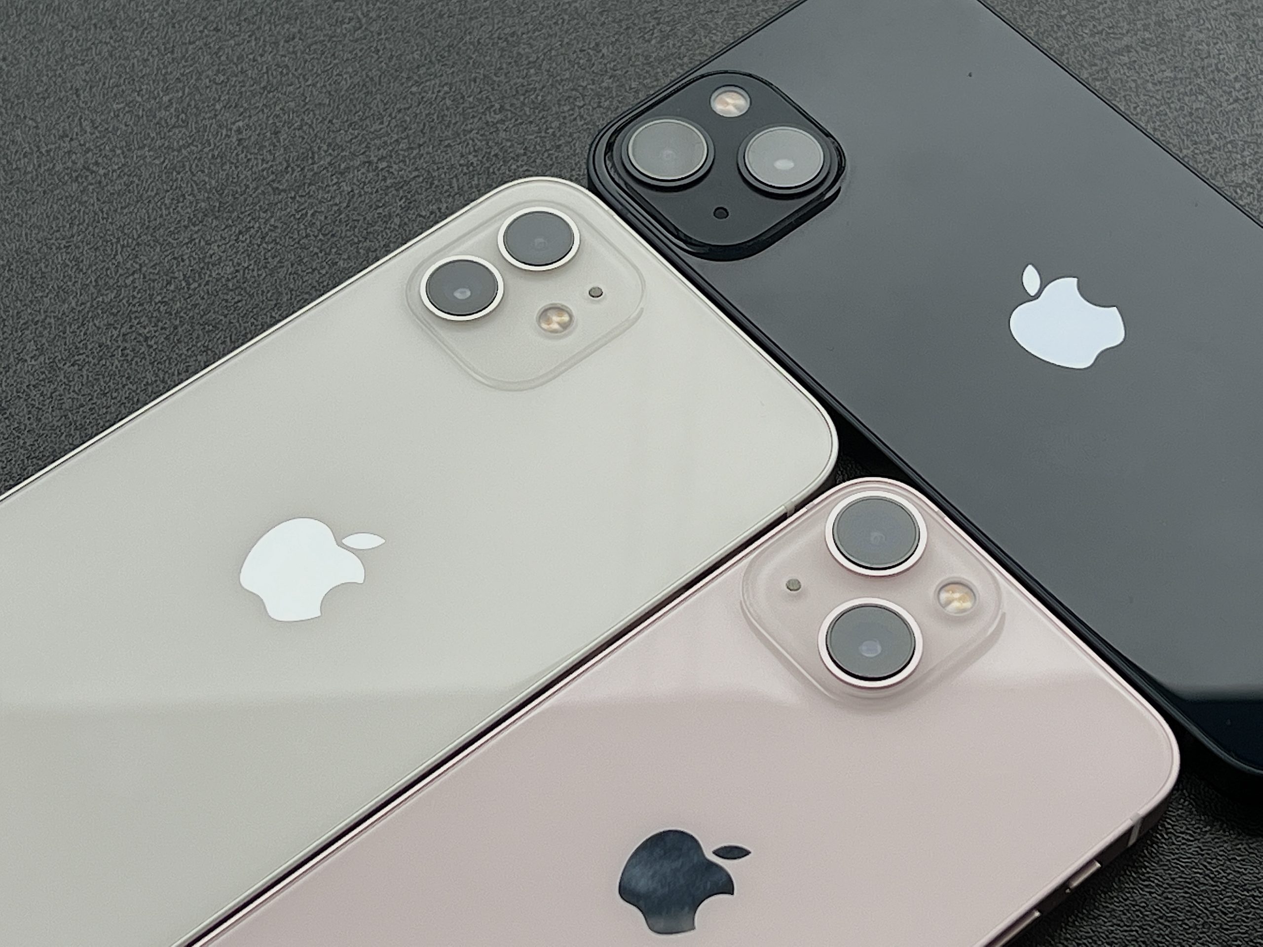 Valkoinen iPhone 12, keskiyö iPhone 13 ja pinkki iPhone 13 mini. Perusmalleissa takakamerat on nyt sijoitettu kohouman vastakkaisiin kulmiin, ei enää allekkain.