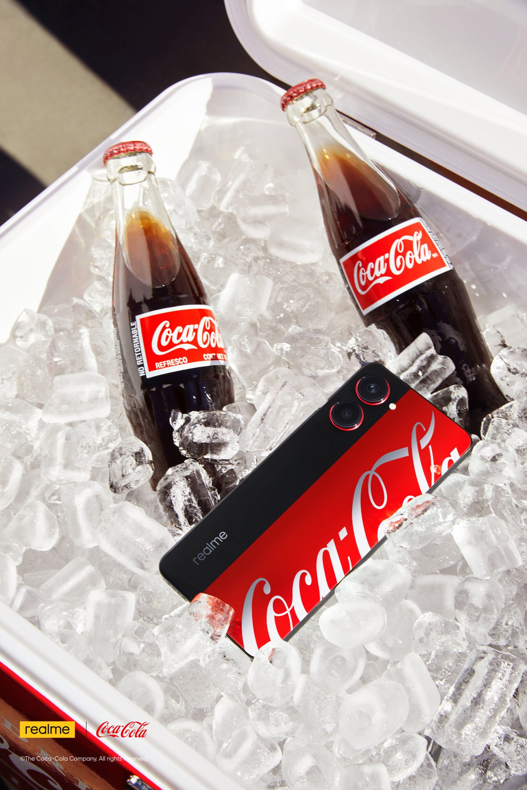 Realme 10 Pro 5G Coca-Cola Edition -älypuhelin yhdessä Coca-Cola-pullojen kanssa.