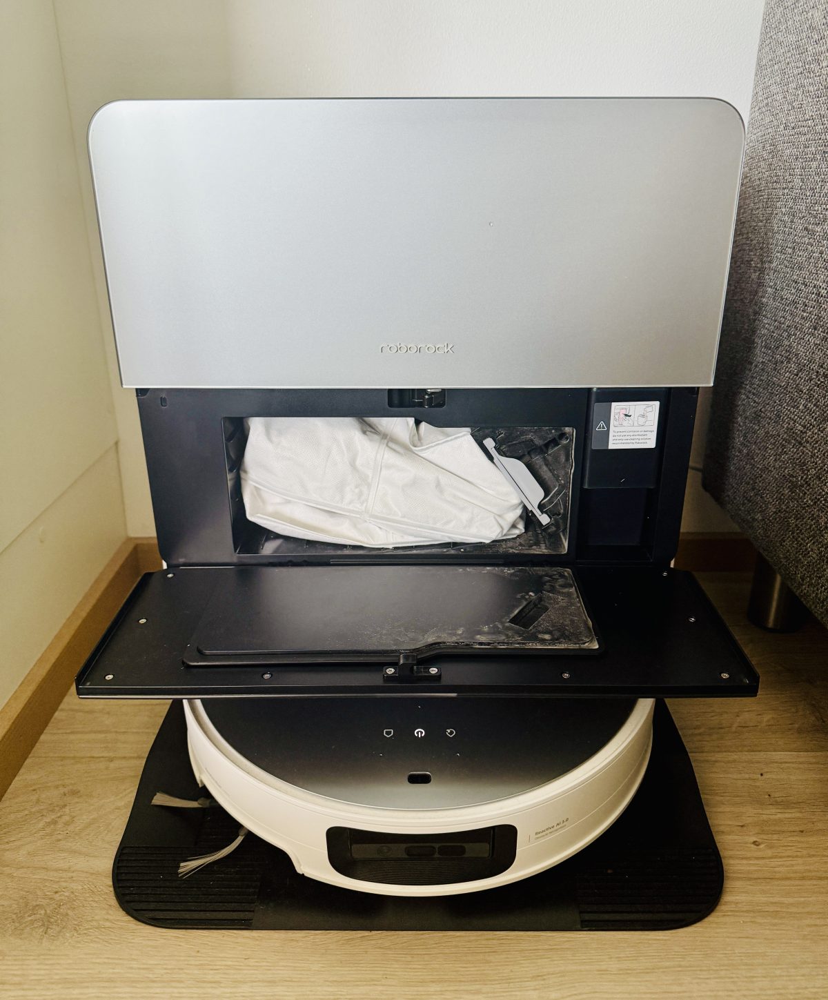 Roborock Saros 10:n telakka. Keskellä valkoinen pölypussi ja sen oikealla puolella puhdistusaineen säiliö.