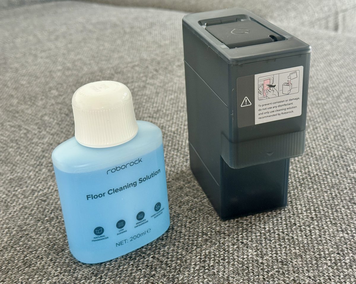 Roborockin puhdistusainetta sekä puhdistusaineen säiliö telakasta.